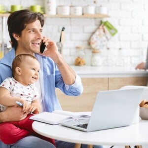 father talking on phone holding baby
